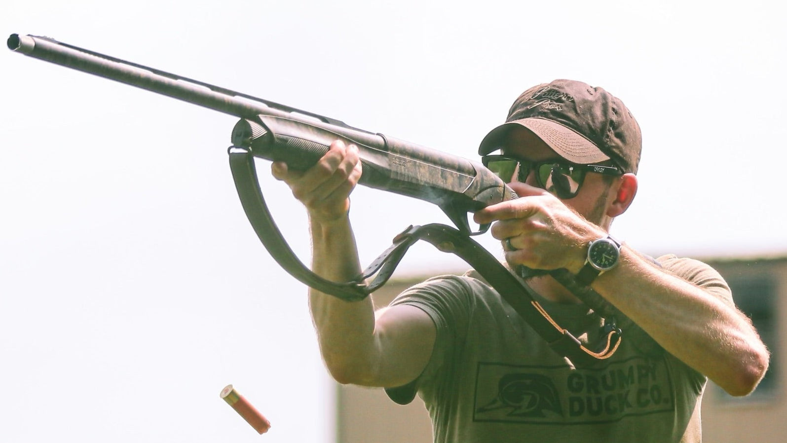 Man in camouflage cap and shirt holding a rifle with a blurred background
